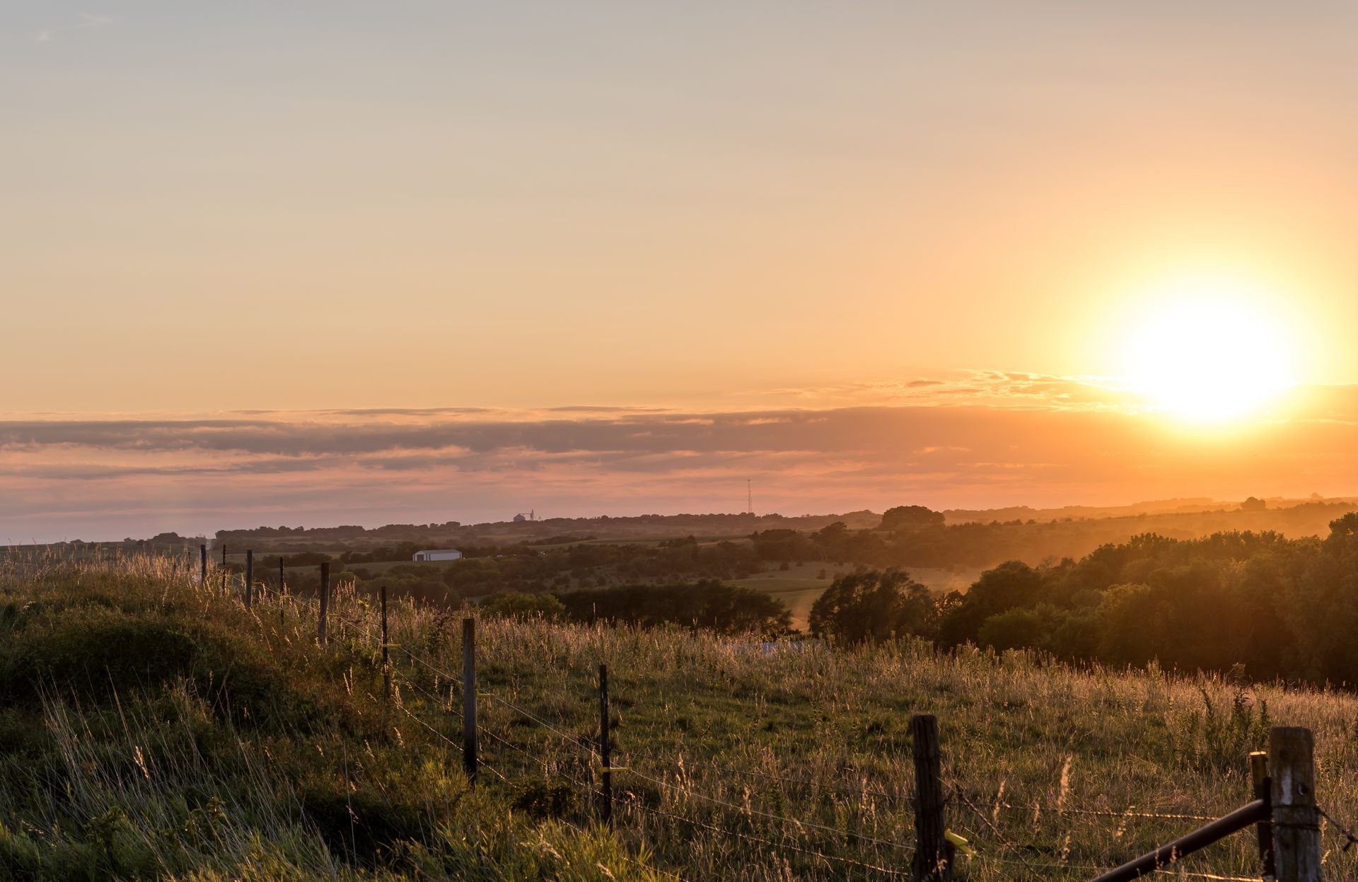 Open rural acreage with a post and wire fence at sunrise