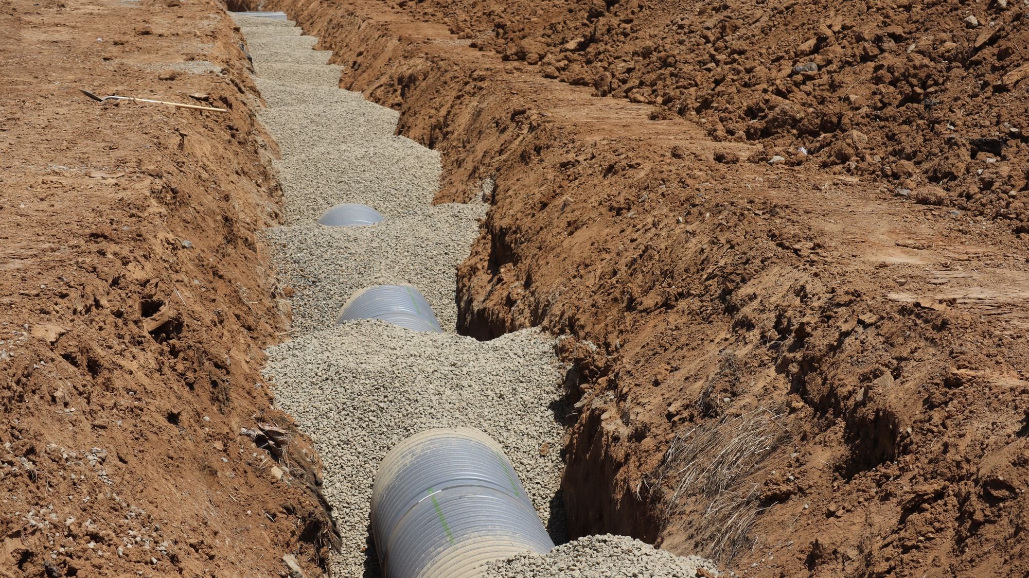 Corrugated drainage pipe laid in a gravel trench at a residential site