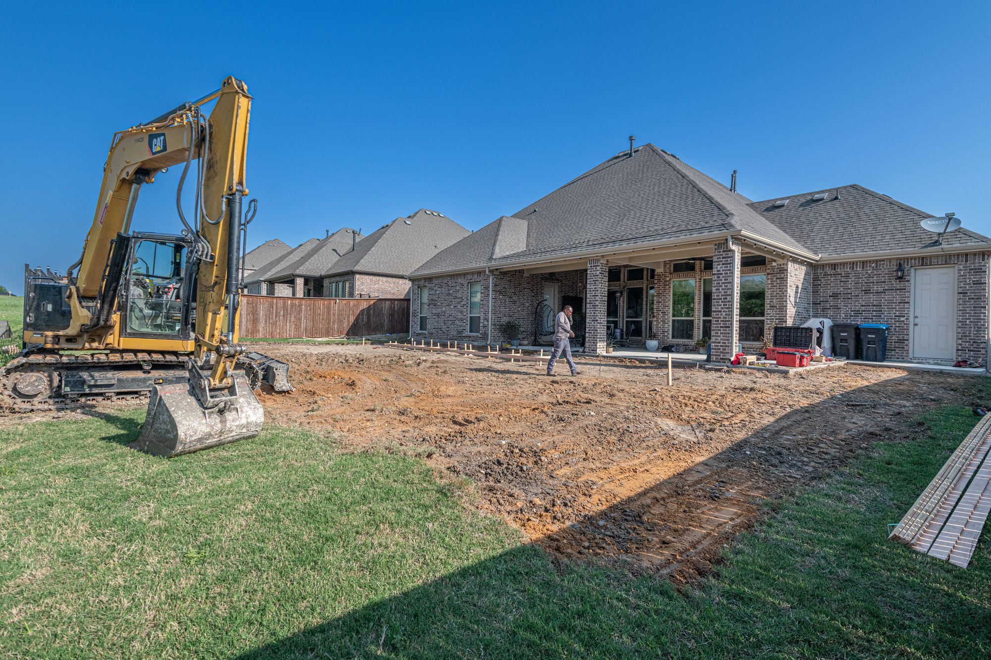 Excavator preparing a residential backyard for new construction