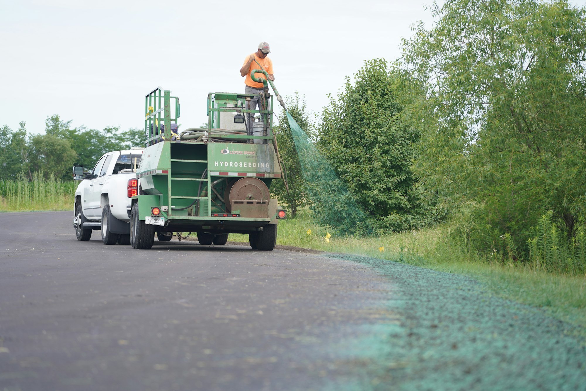 Hydroseeding truck and trailer spraying a new lawn area